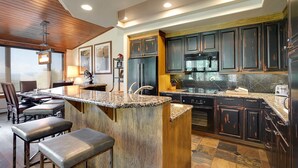 A modern kitchen with dark wood cabinets, granite countertops, and stainless steel appliances.