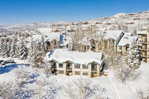 Une station de ski enneigée comprenant plusieurs bâtiments, dont un grand chalet doté de balcons et surplombant les montagnes.