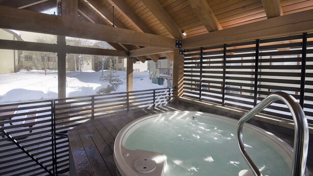 A wooden spa area with a hot tub, wooden beams, and a view of a snowy landscape. - SHB26 | Minutes from Slopes | Free City Bus | Hot Tub (Steamboat Springs)