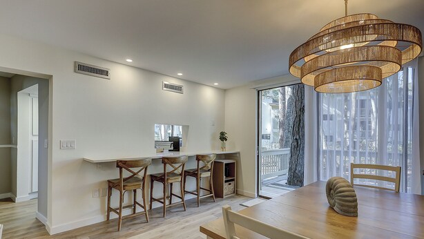 A modern kitchen with a dining area, wooden chairs, a round table, and a unique hanging light fixture. - Stunning Pool Views! Close to Coligny Plaza/Beach (Hilton Head Island)