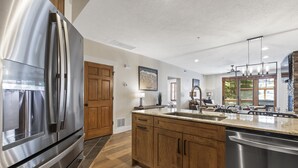 A modern kitchen with stainless steel appliances, wooden cabinets, and a large island with a sink. - Walk to Lifts and Main Street - Private Hot Tub I Managed by Park City Lodging (Park City)