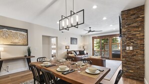 A dining area with a wooden table set for six, surrounded by chairs, with a map on the wall and a stone accent wall. - Walk to Lifts and Main Street - Private Hot Tub I Managed by Park City Lodging (Park City)