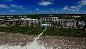 A resort with multiple multi-story buildings, a central pool, and a sandy beach area. - Heated Oceanfront Pool with Hot Tub! Close to Coligny! (Hilton Head)