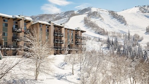 Un hotel de varios pisos con balcones, con una imponente montaña nevada al fondo.