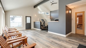Una habitación amplia con un banco de madera largo, ventilador de techo y cinta de correr.