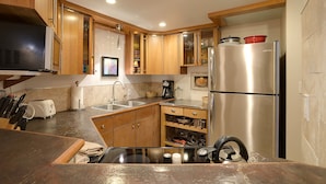 Una cocina compacta con armarios de madera, un refrigerador de acero inoxidable y un horno empotrado.
