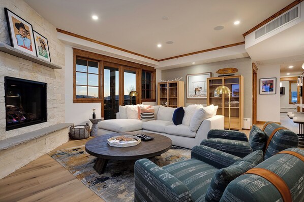 A spacious living room with a fireplace, large windows, and a cozy seating area.