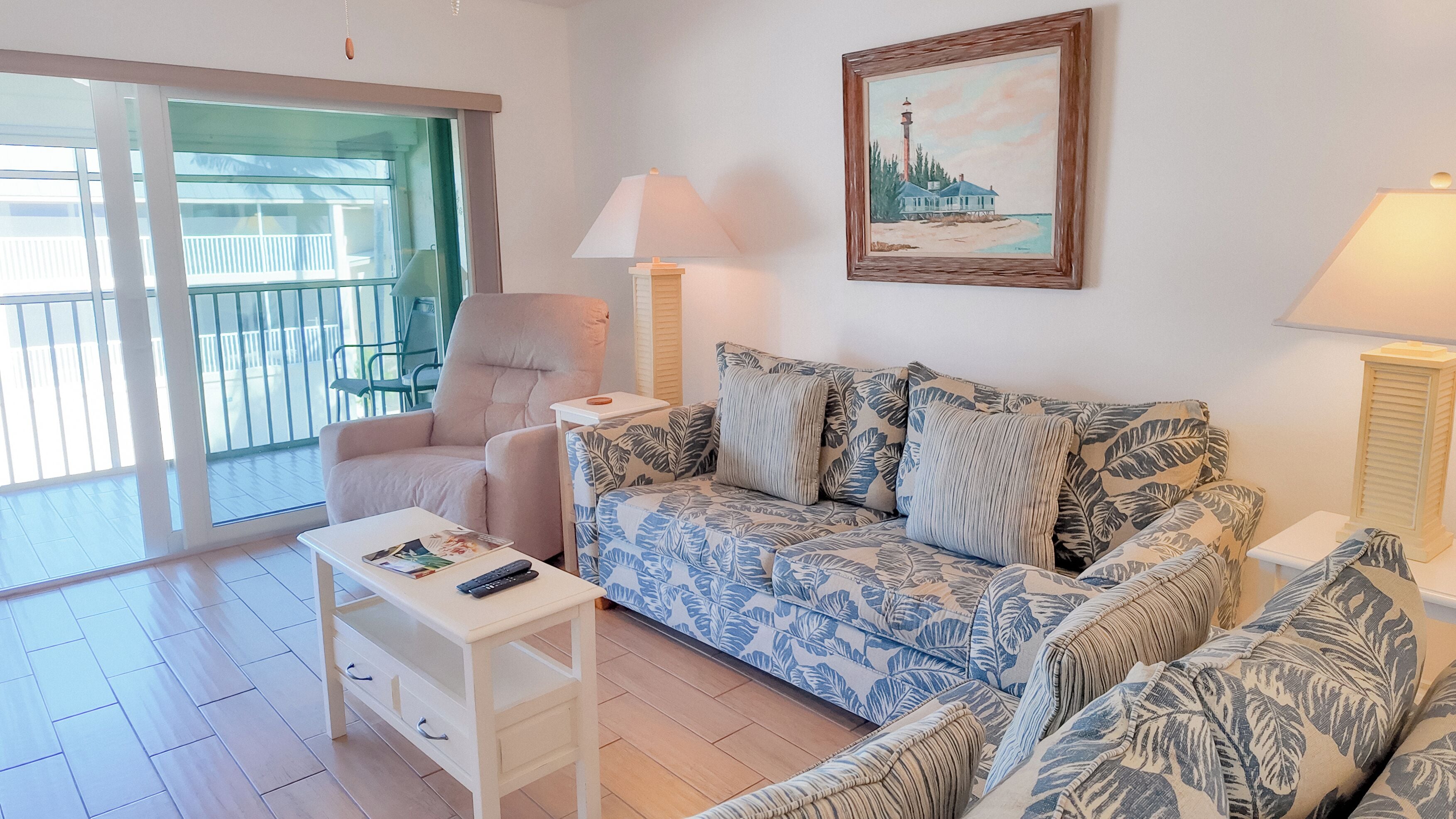 Una sala de estar con un sofá, una silla, una mesa y un cuadro en la pared.