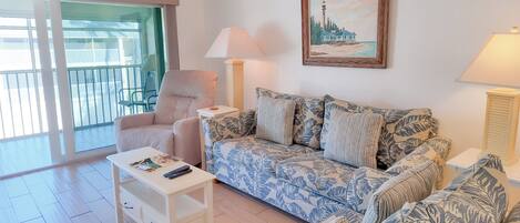 Una sala de estar con un sofá, una silla, una mesa y un cuadro en la pared.