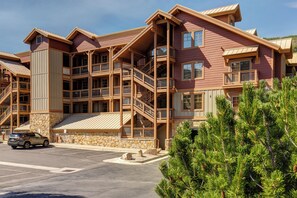 A multi-story building with a stone foundation, wooden balconies, and a parking lot. - Great location to Old Town/Main Street| Hot Tub | Managed by Park City Lodging (Park City)