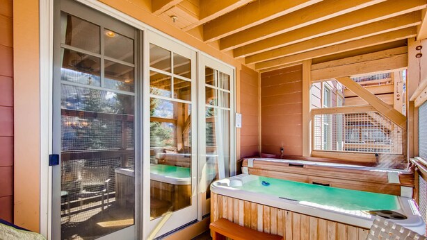 A hot tub area with a wooden deck, a sliding glass door, and a staircase leading to an upper level. - Managed by Park City Lodging-Great location, just a short walk to Main Street. (Park City)