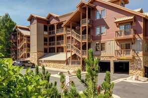 A multi-story building with a stone facade, multiple balconies, and a parking area. - Great location to Old Town/Main Street| Hot Tub | Managed by Park City Lodging (Park City)