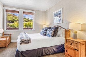A bedroom with a bed, two windows, a bedside table, a lamp, and a picture on the wall. - Great location to Old Town/Main Street| Hot Tub | Managed by Park City Lodging (Park City)