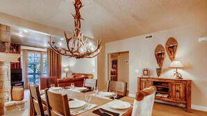 A dining area with a wooden table set for four, a fireplace, and a chandelier. - Managed by Park City Lodging-Great location, just a short walk to Main Street. (Park City)