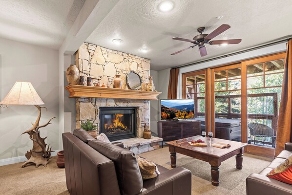 A living room with a stone fireplace, leather sofa, and a television. - Great location to Old Town/Main Street| Hot Tub | Managed by Park City Lodging (Park City)