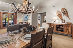 A dining area with a wooden table set for four, surrounded by chairs. A chandelier with antler branches hangs above. - Great location to Old Town/Main Street| Hot Tub | Managed by Park City Lodging (Park City)
