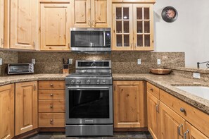 Full kitchen with wood cabinetry, granite countertops, stainless steel range, and microwave. - Great location to Old Town/Main Street| Hot Tub | Managed by Park City Lodging (Park City)