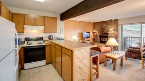 Una cocina compacta con armarios de madera, estufa y televisor.