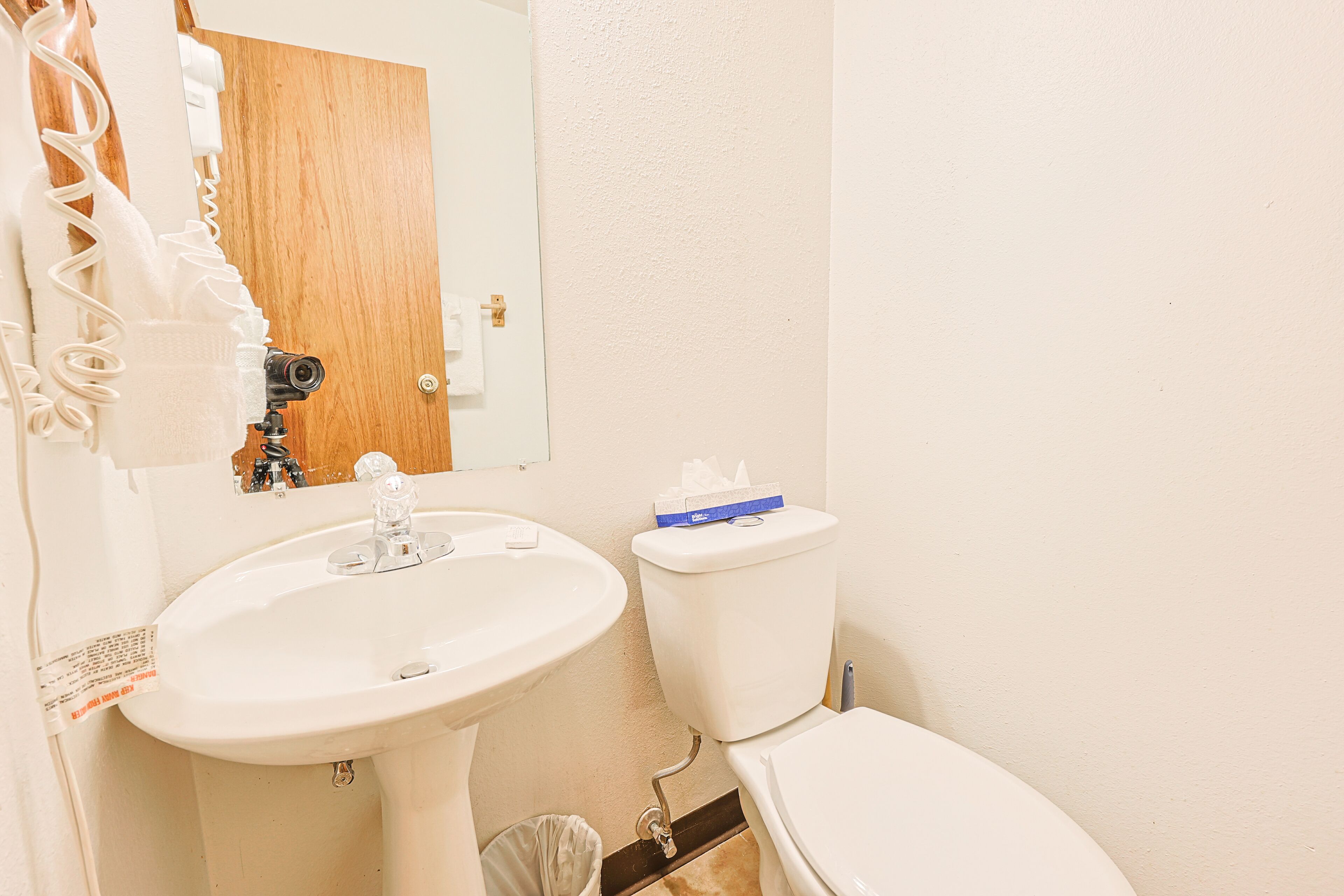 Une salle de bain avec un lavabo blanc, des toilettes et un miroir.