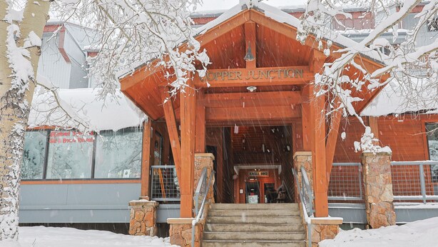 A wooden building with a sign reading "Upper Junction" and a staircase leading up to the entrance. - Center Village Ski In/Out Perfectly decorated and sleeps 6 Walk to everything (Copper)