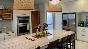 Una cocina moderna con dos amplias encimeras tipo isla, electrodomésticos de acero inoxidable y un ventanal grande.