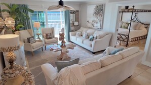 Ein geräumiges Wohnzimmer mit einem weißen Sofa, Sesseln, einem Couchtisch und einem dekorativen Mittelstück.