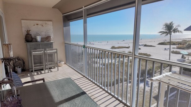 Ein Balkon mit Blick auf den Strand, inklusive Tisch, Stühle und einer Zierwand.