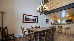 A dining area with a wooden table and chairs, a chandelier, and framed pictures on the wall.