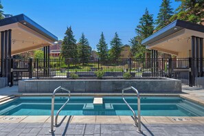 A swimming pool with metal railings, a concrete deck, and a view of a residential area with trees and houses. - Creekside Condo Near Main Street |Pool and Hot Tub| Managed by Park City Lodging (Park City)