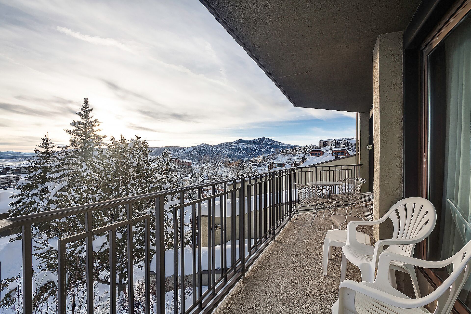 Un balcon offrant une vue sur des arbres et des montagnes enneigés.