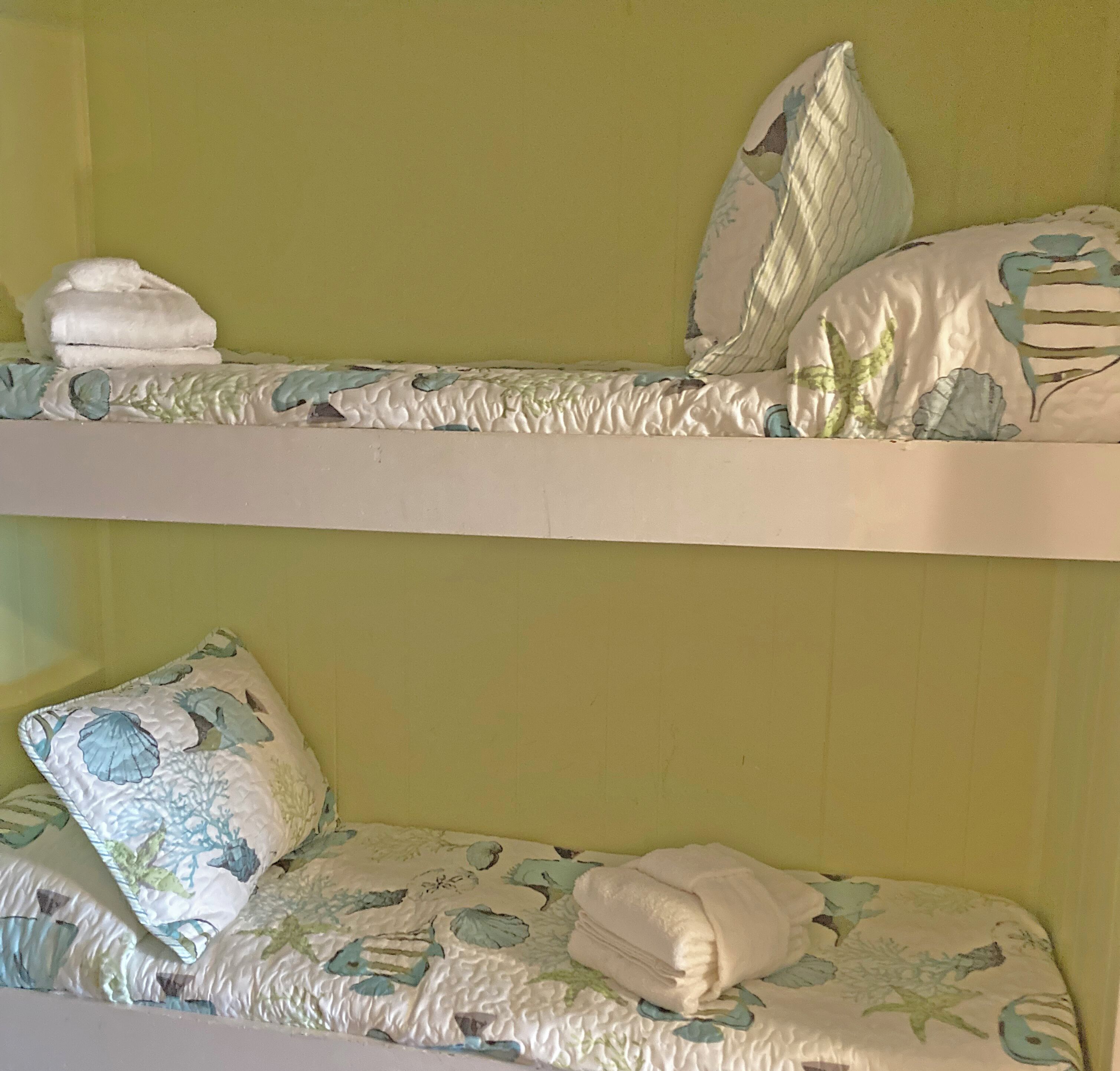A bunk bed with two levels, each with pillows and folded towels.