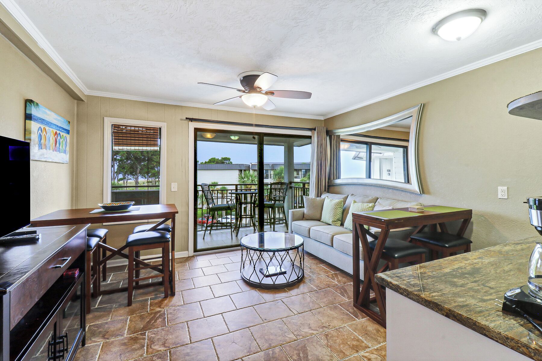 A compact living space with a kitchenette, a dining area, and a seating area with a view of the outdoors.