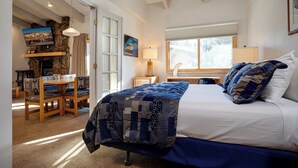 A bedroom with a bed, a desk, a chair, a fireplace, and a window.