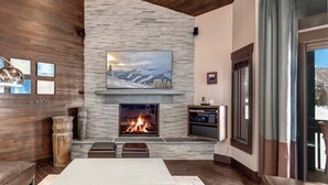 A modern living room with a stone fireplace, a large flat-screen TV, and a cozy seating area. - Managed by Park City Lodging-Premier Townhome in Lower Deer Valley-Ski Shuttle (Park City)