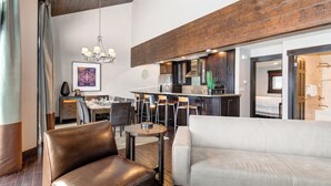 A modern living room with a sofa, a dining area with chairs, a chandelier, and a kitchen area with a bar. - Managed by Park City Lodging-Premier Townhome in Lower Deer Valley-Ski Shuttle (Park City)