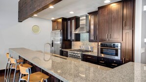 A modern kitchen with granite countertops, stainless steel appliances, and dark wood cabinets. - Managed by Park City Lodging-Premier Townhome in Lower Deer Valley-Ski Shuttle (Park City)