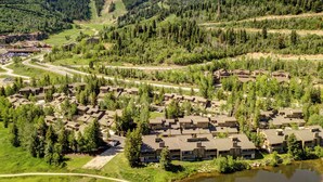 A resort with multiple buildings, a winding road, and a lake. - Managed by Park City Lodging-Premier Townhome in Lower Deer Valley-Ski Shuttle (Park City)