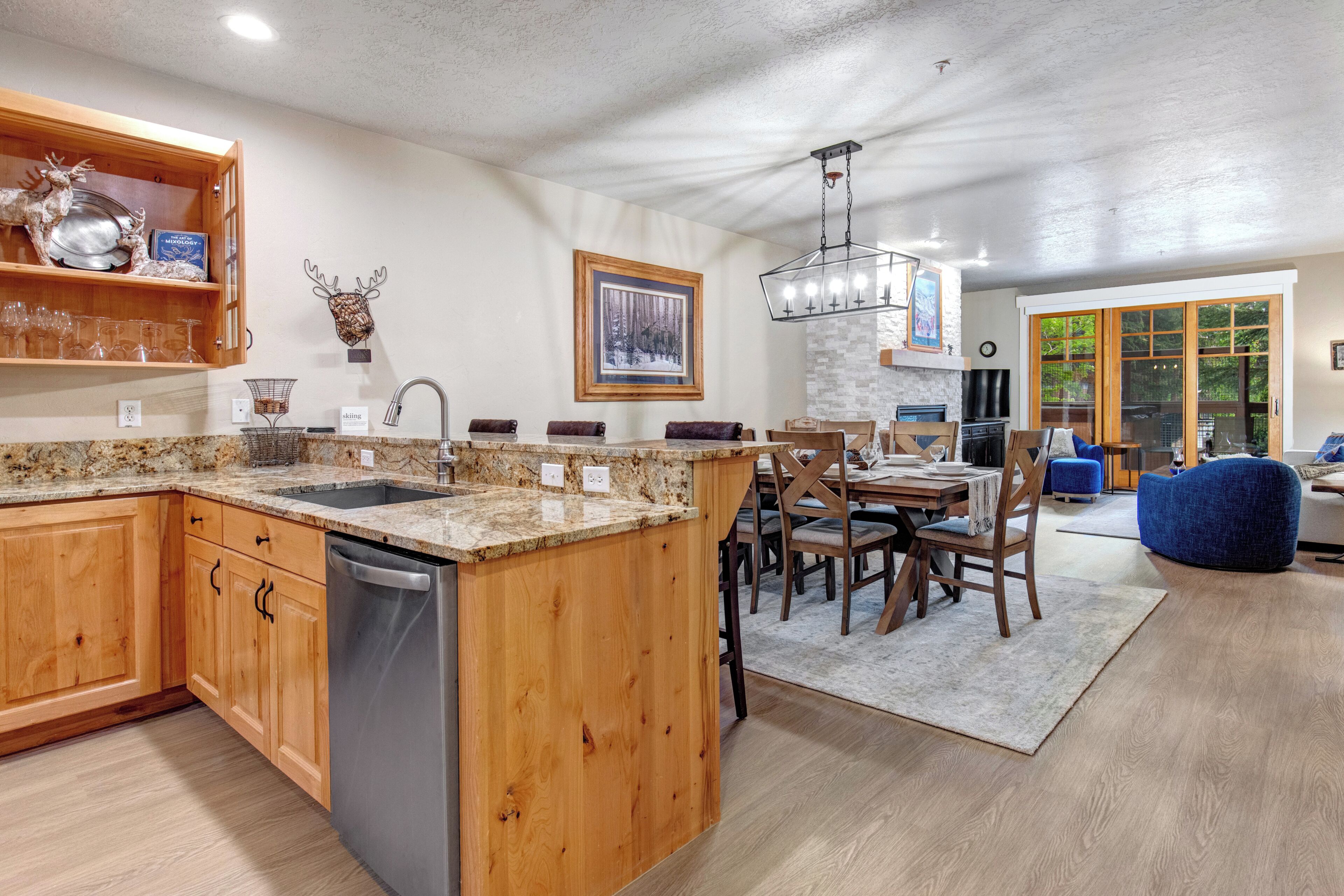 Una cocina con armarios de madera, lavavajillas, encimeras de granito y una zona de comedor con mesa y sillas.