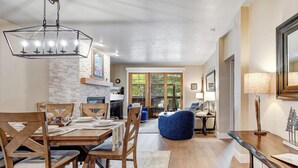 A dining area with a wooden table and chairs, a blue bean bag chair, a hanging light fixture, and a fireplace. - Managed by Park City Lodging-Deluxe Condo Walk to Town Lift and Main Street (PARK CITY)