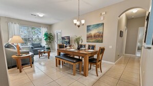 Un salon moderne avec un coin repas, comprenant une table à manger en bois, des chaises, un canapé et un téléviseur.