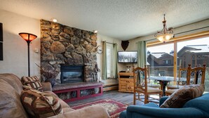 Una sala de estar acogedora con chimenea de piedra, asientos cómodos y vistas al exterior.