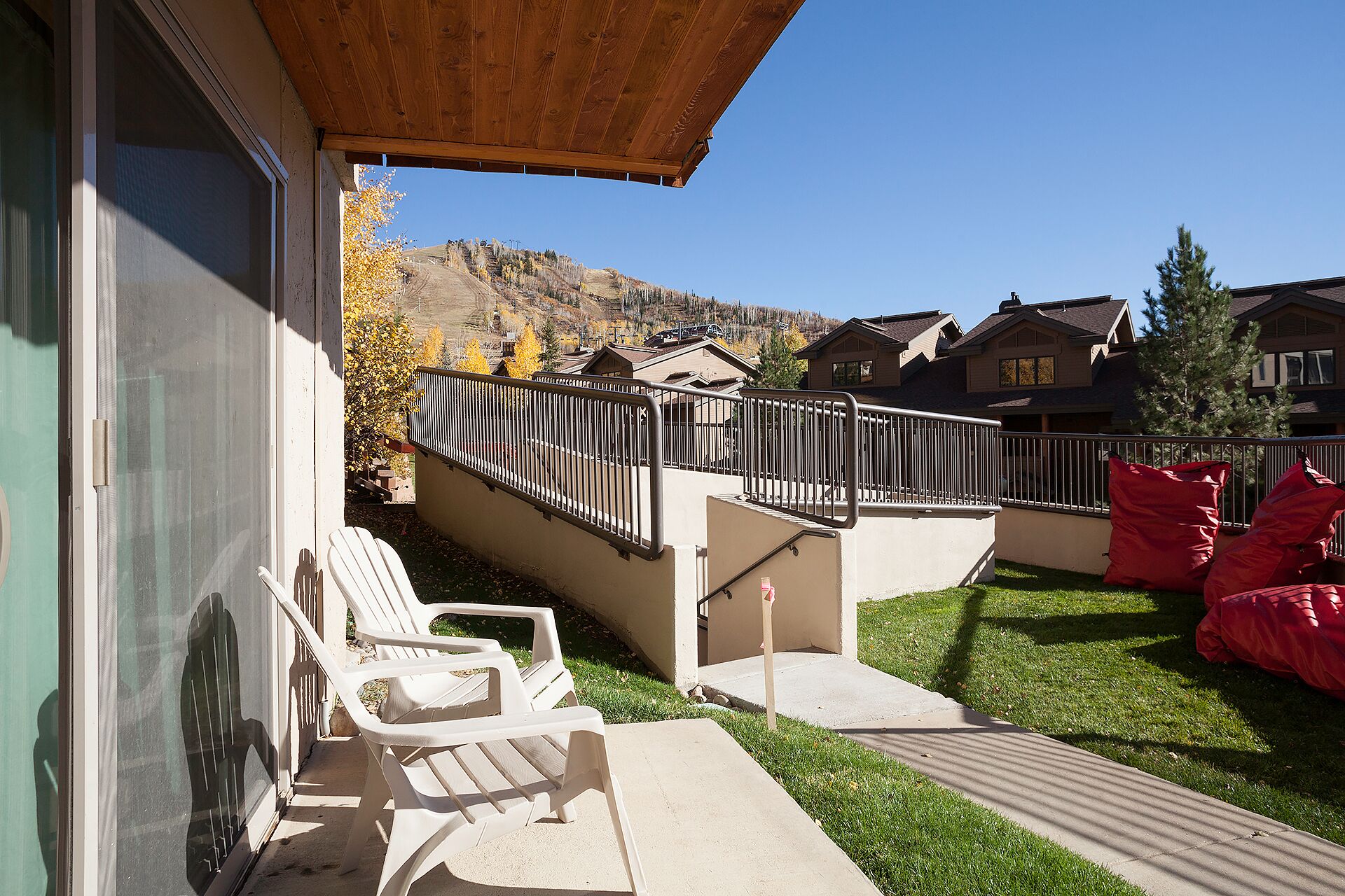 A patio with two white plastic chairs, a concrete pathway, and a metal fence.