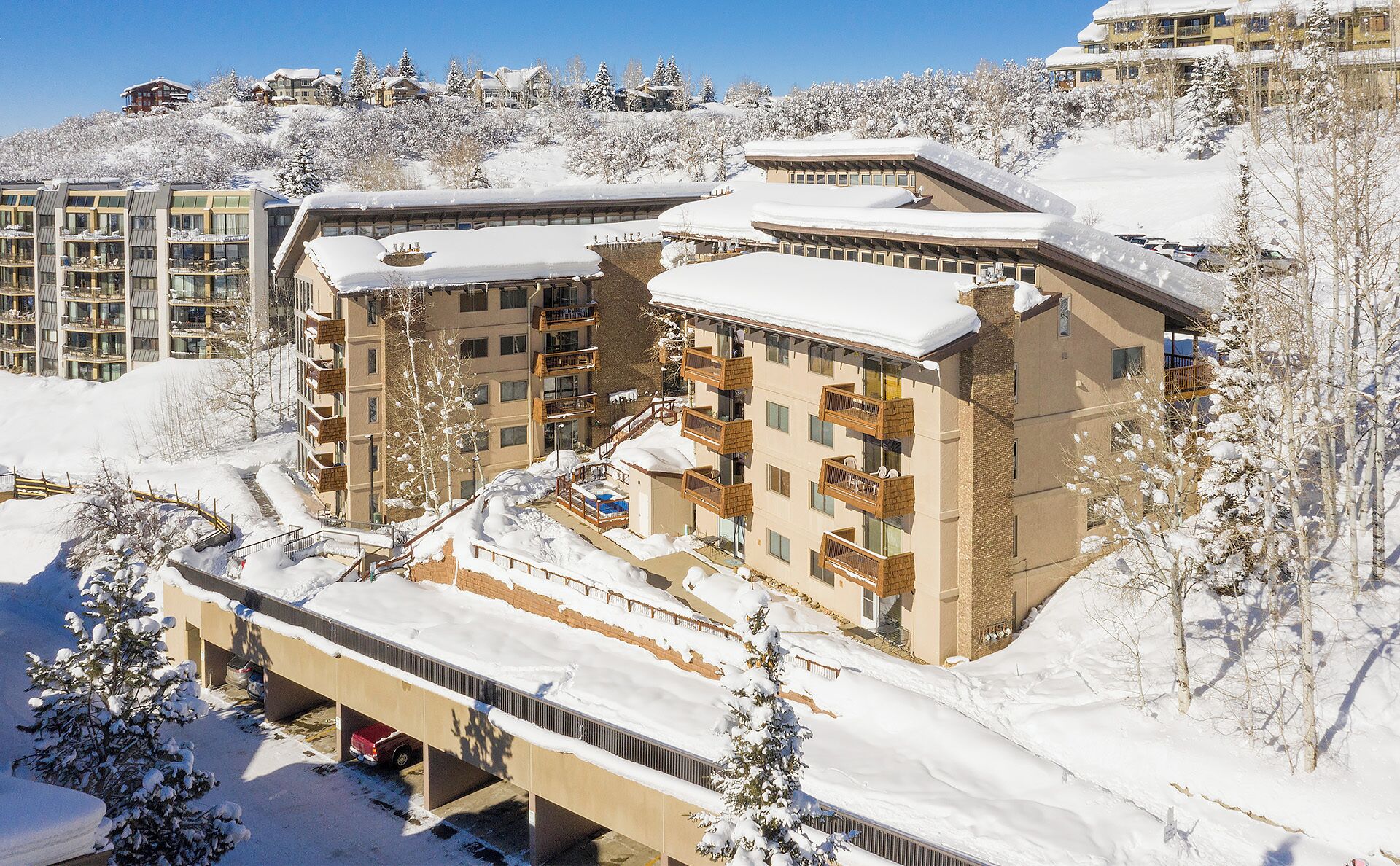 A multi-story hotel with balconies, surrounded by snow-covered trees and buildings.
