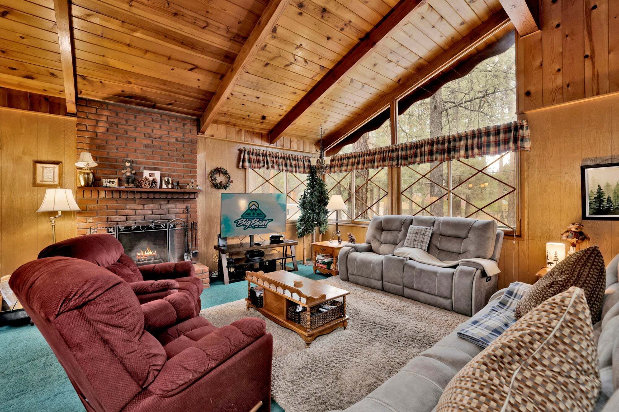 Cozy mountain living room with a stone fireplace, comfy seating, and smart TV—perfect for relaxing evenings, movie nights, and warm cabin vibes after outdoor adventures.