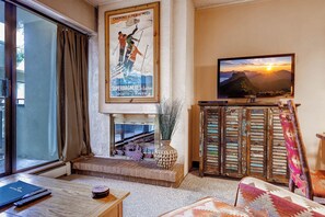 Una sala de estar con un ventanal grande, una chimenea, un televisor y un cartel en la pared.