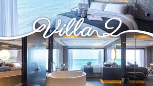 Une chambre d’hôtel luxueuse, dotée d’un grand lit, d’une baignoire et offrant une vue sur la mer.