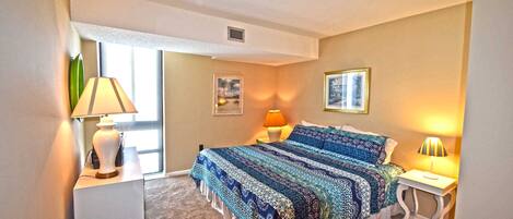 A bedroom with a bed, two bedside tables, a window, and a door.