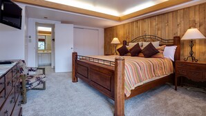 A bedroom with a wooden bed, bedside lamps, a TV mounted on the wall, and a wooden wardrobe. - GSQ32 | Nice Views | Huge Private Deck | Steps from Steamboat Square (Steamboat Springs)