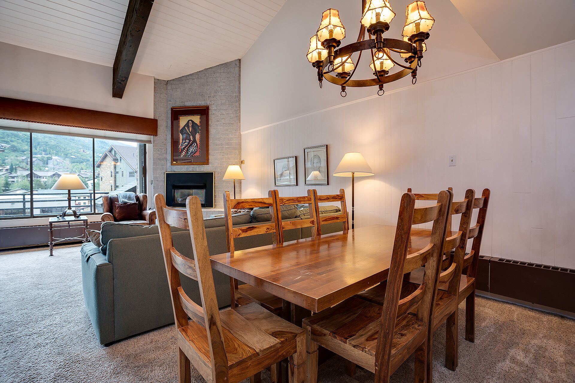 Een eetgedeelte met een houten tafel en stoelen, een open haard en een kroonluchter.