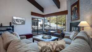 A cozy living room with a fireplace, comfortable seating, and a large window offering a scenic view. - GSQ32 | Nice Views | Huge Private Deck | Steps from Steamboat Square (Steamboat Springs)